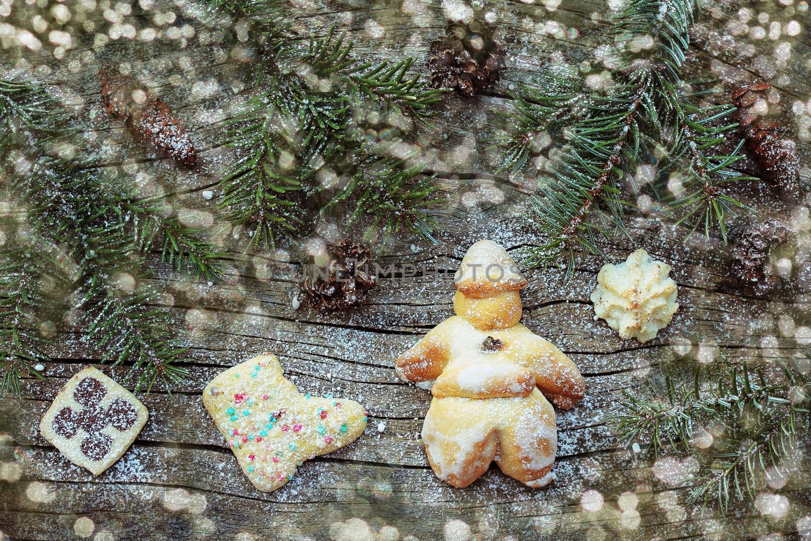 Cookies, Santa Claus, fir twigs and glitter spots on a wooden background. Various Christmas biscuits on wood