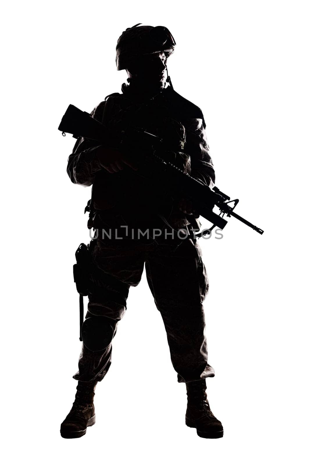 Full length, low key studio shoot of fully equipped army soldier in camo uniform and helmet, armed with pistol and assault service rifle with underbarrel grenade launcher isolated on white background