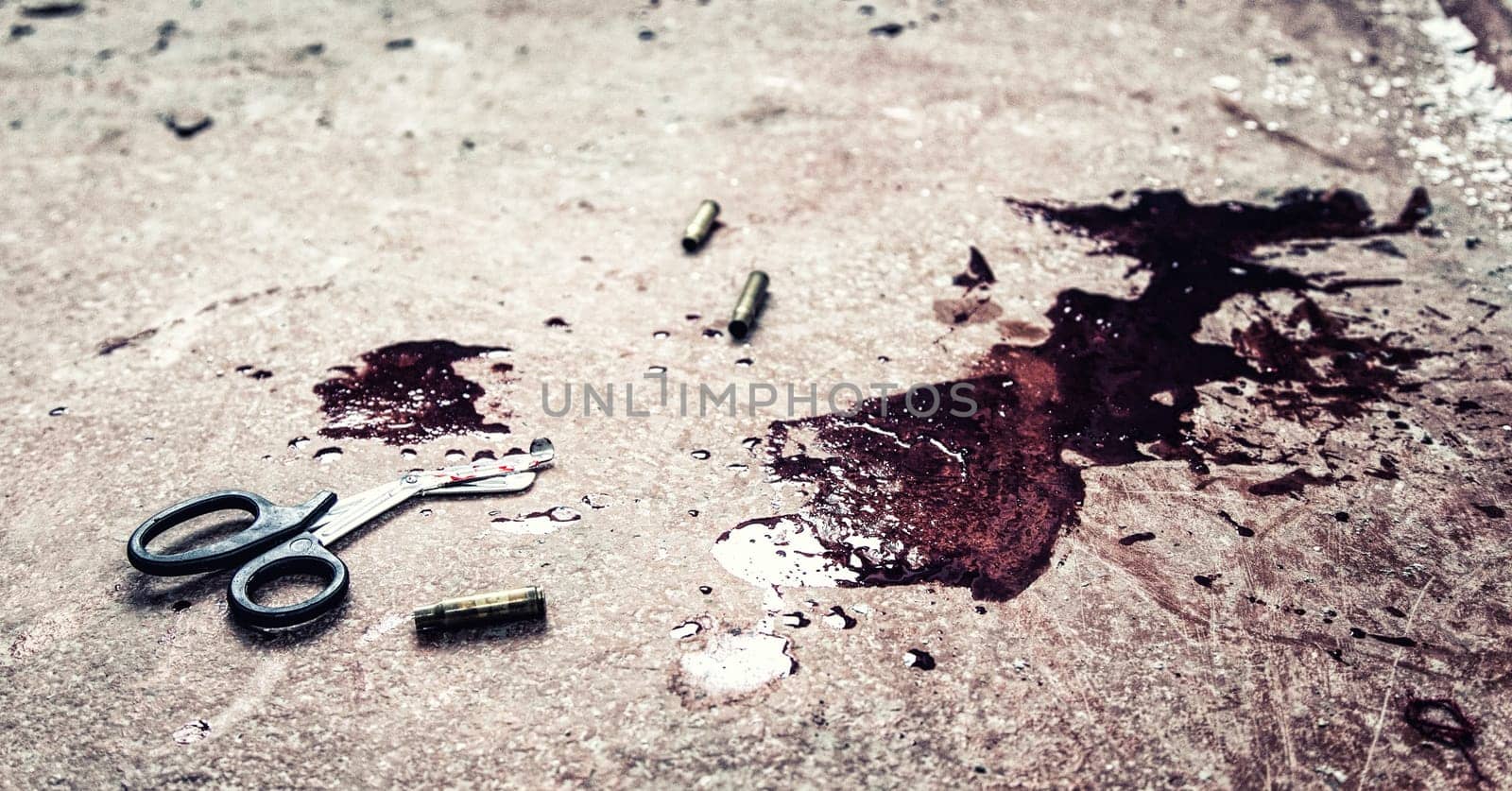 Trauma shears or bandage scissors lying on floor with stains of human blood around. Blood loss and bleeding stop, emergency medical aid for gunshot wounds, tactical combat casualty care on battlefield
