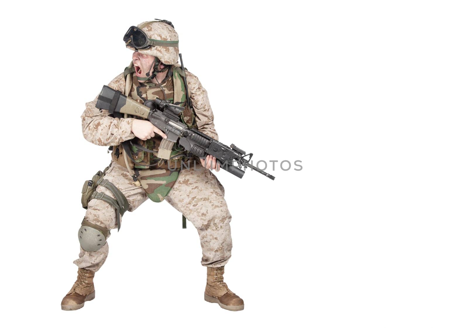 Studio shoot of modern infantry soldier, U.S. marine rifleman in combat uniform, helmet and body armor, screaming and crouching down with assault service rifle in hands isolated on white background