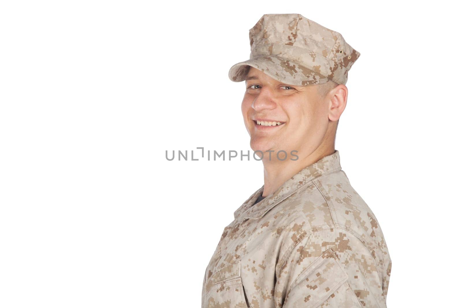 Shoulder studio portrait of smiling United States army soldier, marine infantry or military contractor in camouflage combat uniform and patrol cap