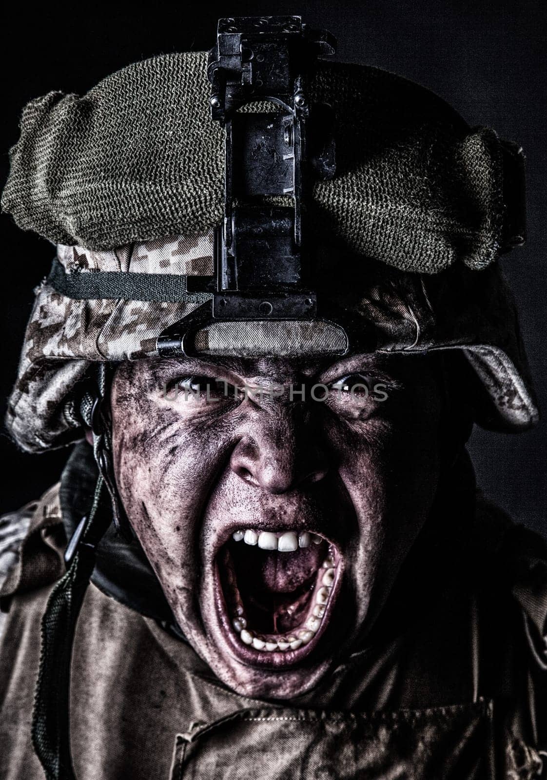 Close up portrait of aggressive screaming army soldier, attacking with mad yelling commando, roaring and grimacing marine in camouflage helmet with sweaty, dirty face studio shoot on black background