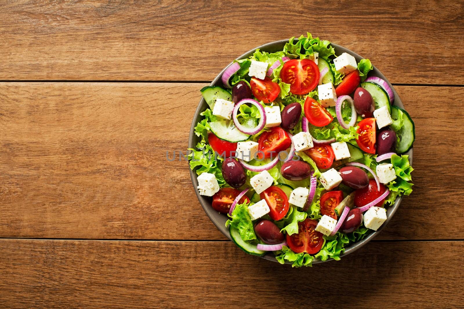 Salad with feta cheese and fresh vegetables on wooden background. Greek salad.