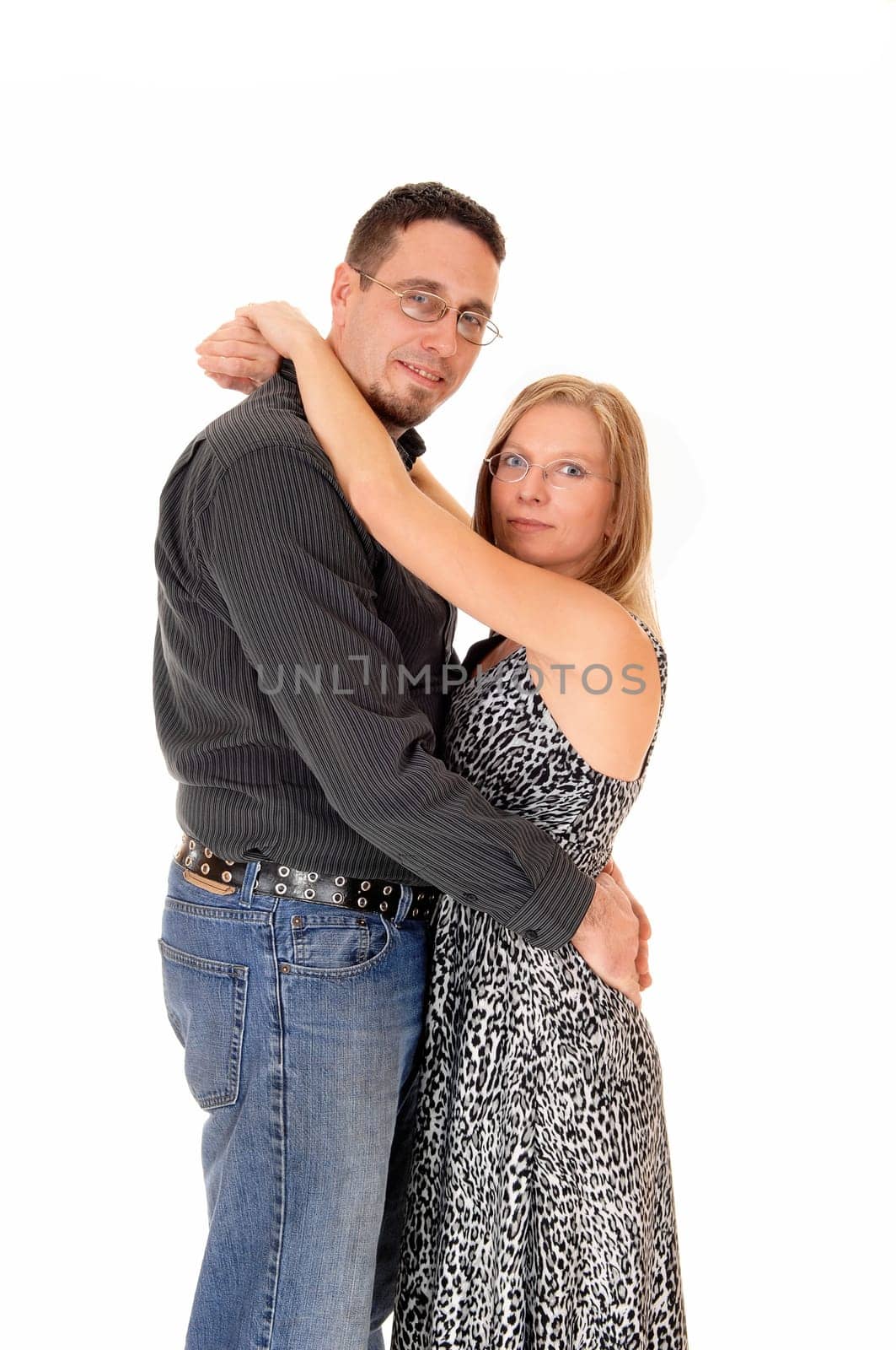 A lovely young couple standing for white background, hugging each.other and facing each other, looking into the camera..