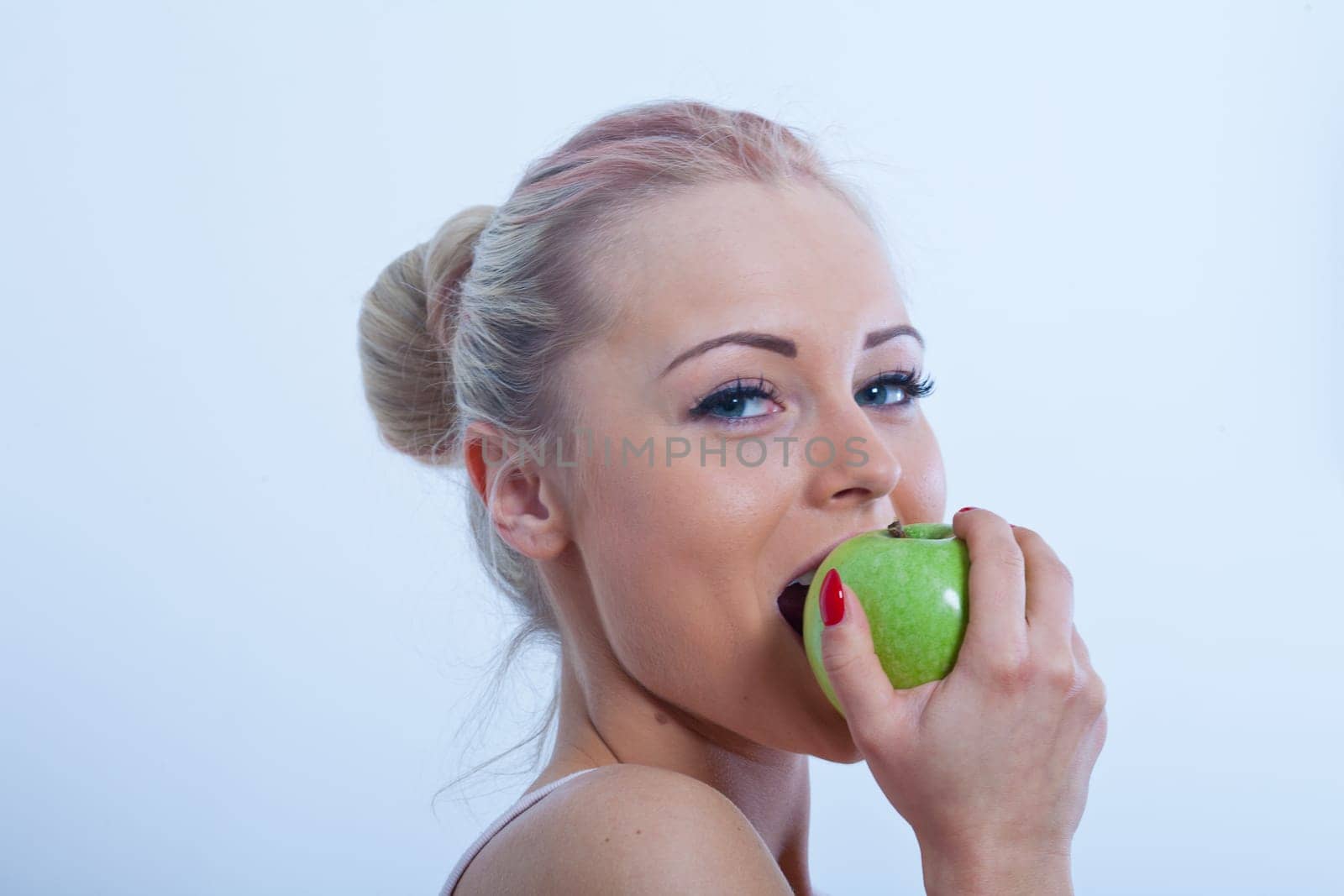 nice smile of a beautiful girl biting a green apple