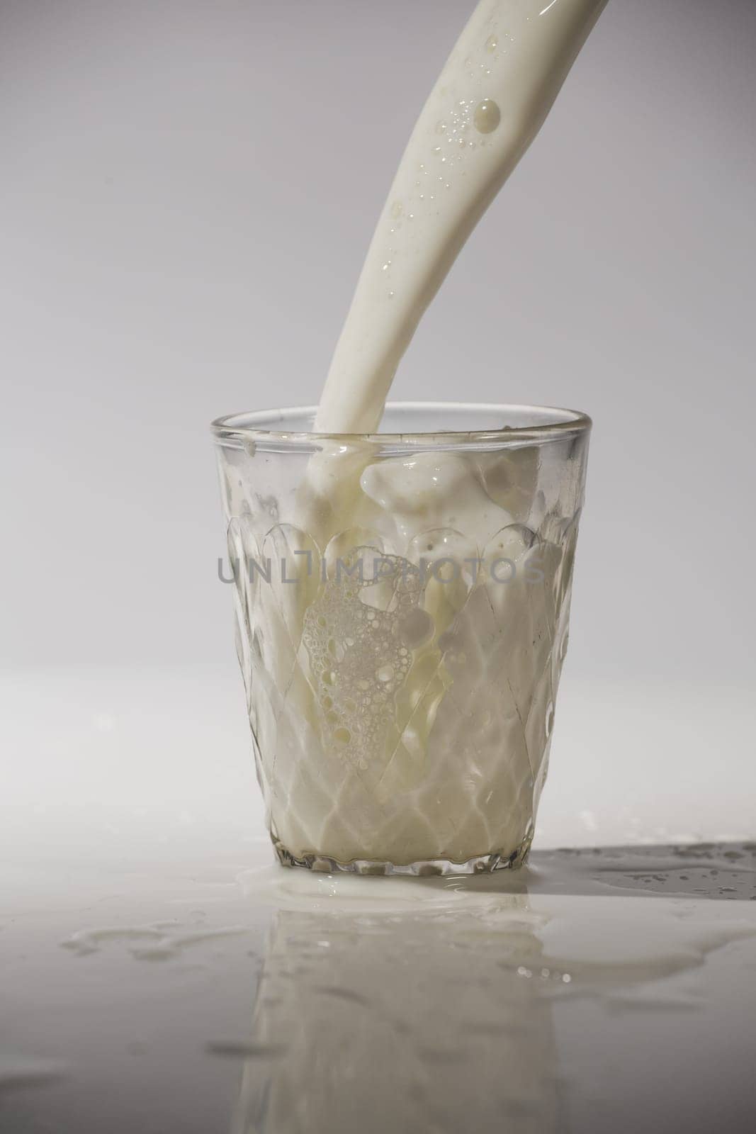 pouring milk in a glass isolated against white background