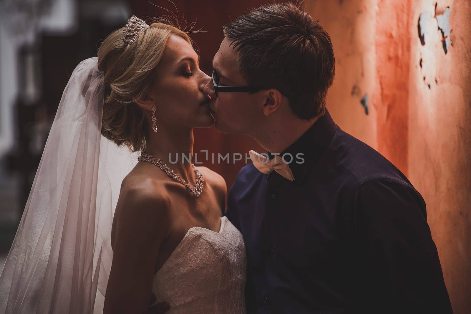 Closeup portrait of bride and groom kissing in ancient tunnel made of bricks