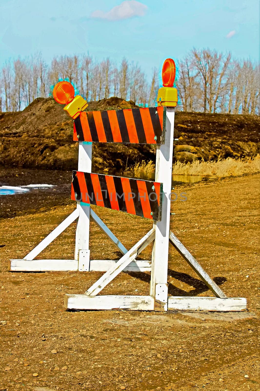 A construction barricade on a gravel road.