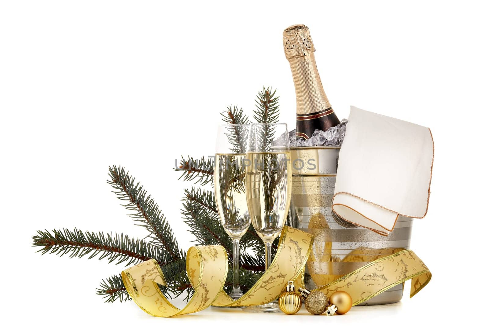 Still life with champagne bottle standing in a bucket with ice, two full champagne flutes and Christmas ornaments isolated on a white background with copy space, Christmas and New Year celebration