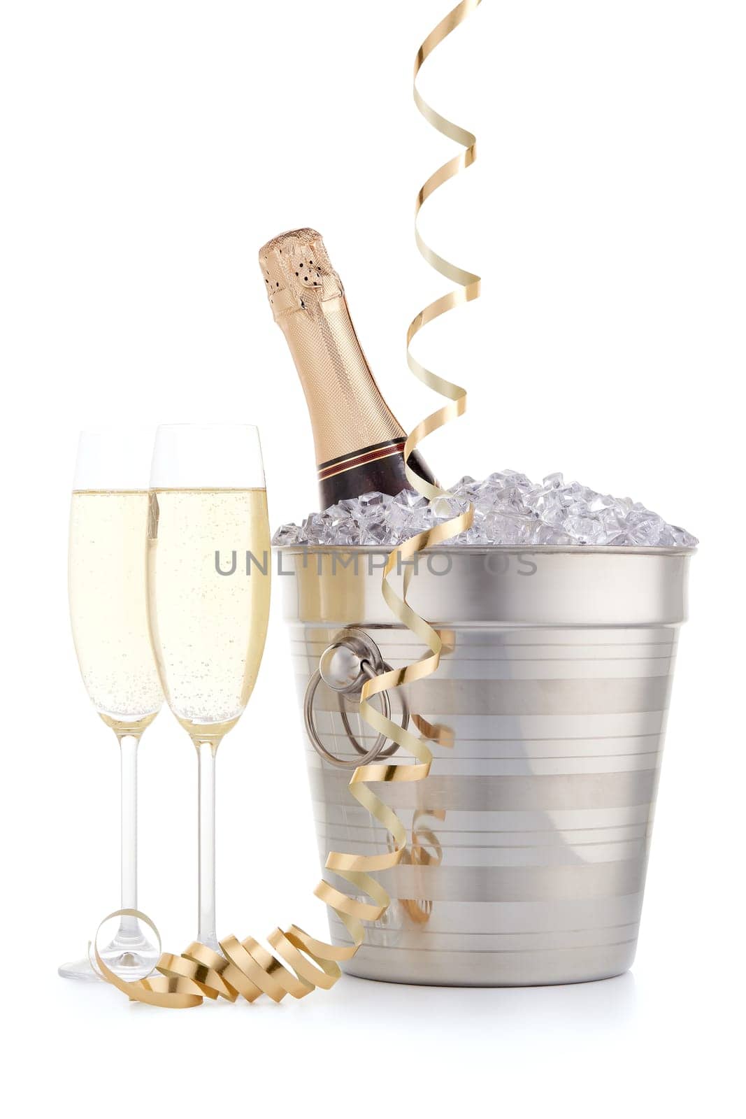 Still life with cooled champagne bottle standing in a bucket with ice, two full champagne flutes and gold streamer isolated on a white background, Christmas and New Year celebration