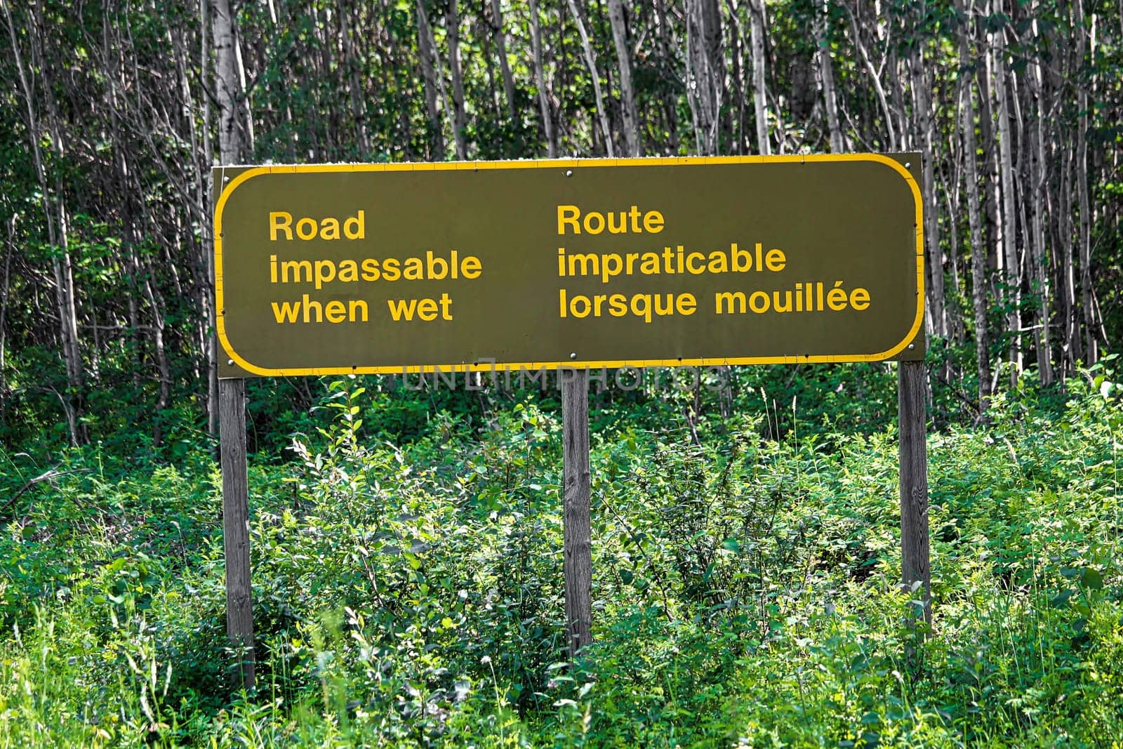 A bilingual road impassable when wet sign.