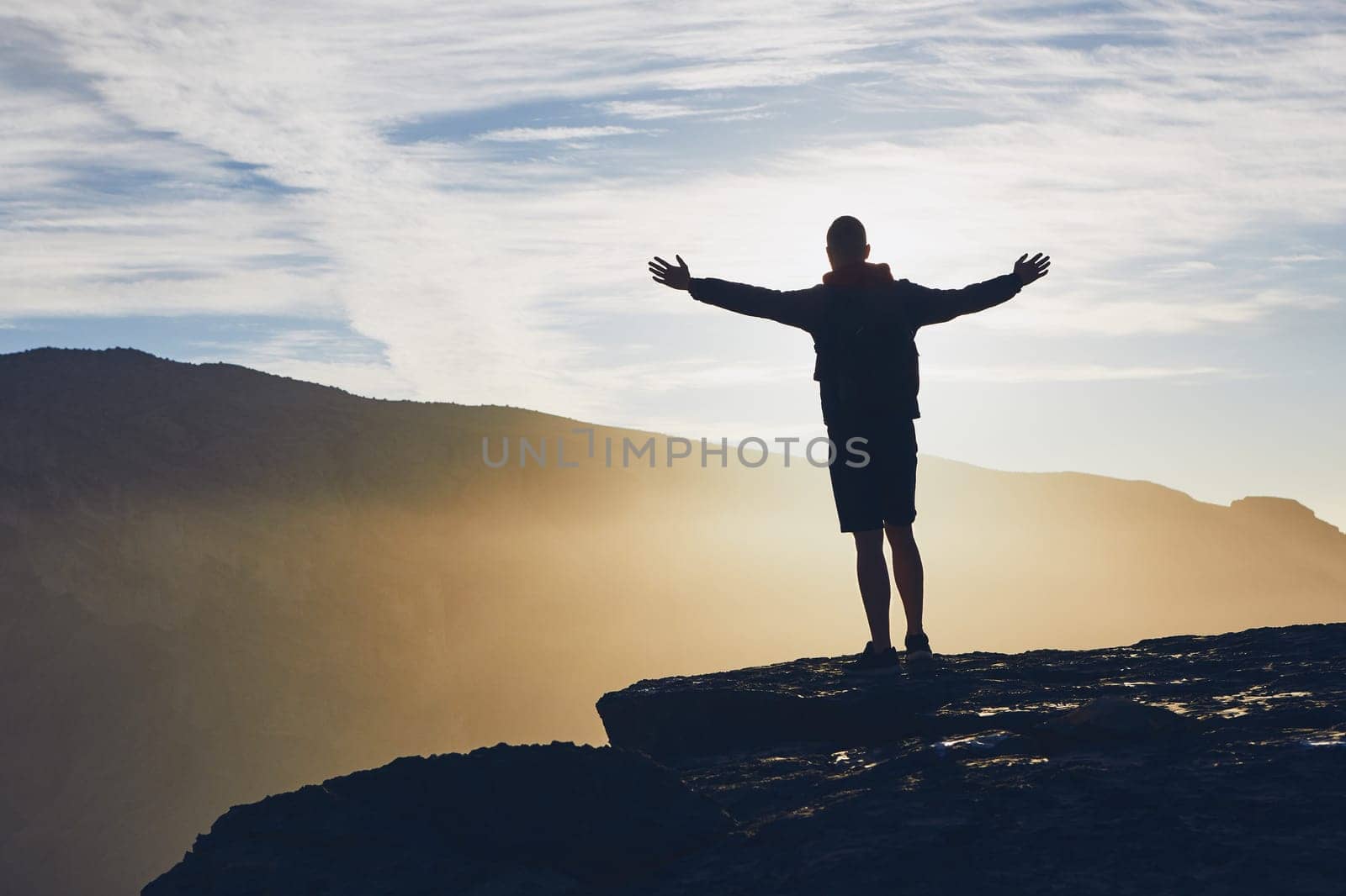 Silhouette of happy tourist on the edge of cliff at sunrise. Jebel Akhdar, Grand Canyon of Oman.