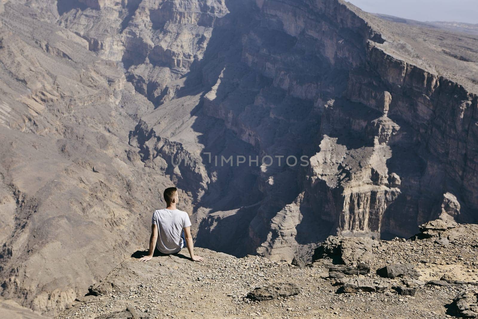 Young tourist resting on the edge of cliff. Jebel Akhdar, Grand Canyon of Oman
