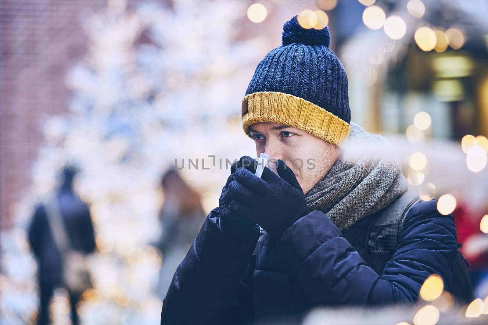 Young man drinking mulled wine. against illuminated christmas trees. Munich, Germany.