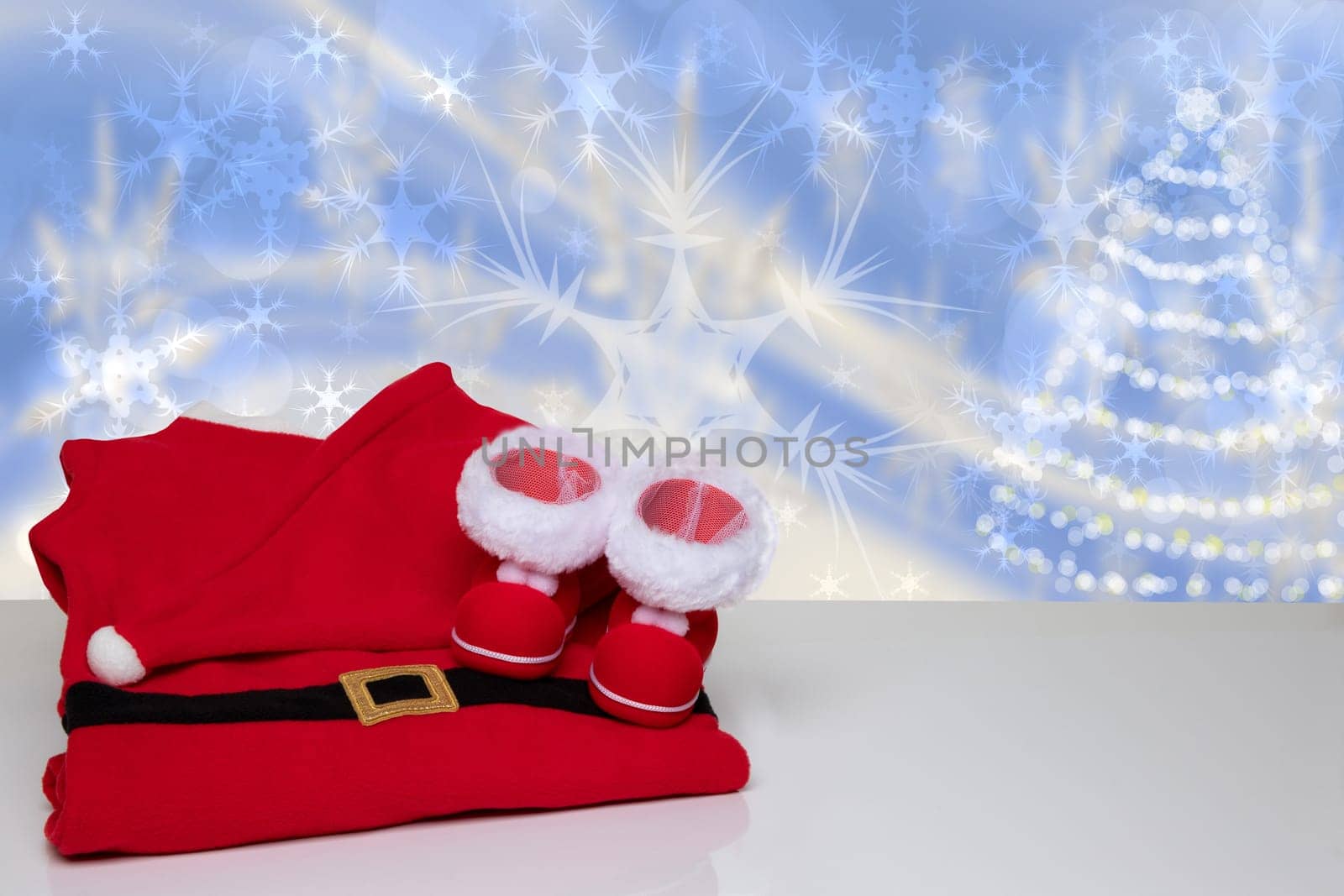 Christmas background. Table top christmas winter decoration background with Santa Claus costume and Santa boots on bright table with space over abstract festive blue christmas compostion.