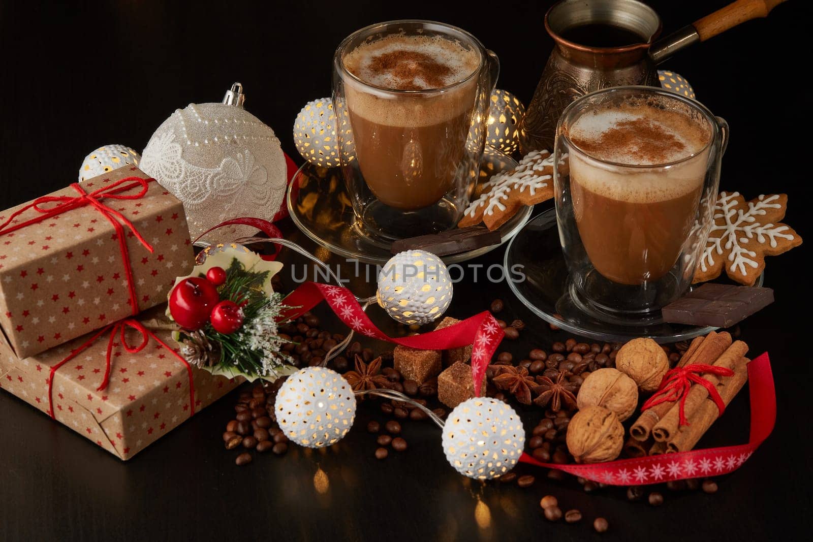 Still life with two cups of coffee, gingerbread cookies, gift box and Christmas decorations on a dark background with LED lights garland . Christmas and New Year treat.