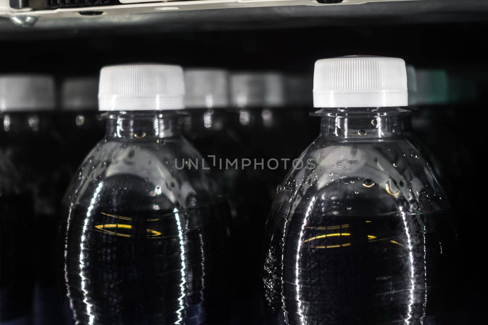 Soda Bottles in Vending Machine White Bottle Caps Black Liquid Rows