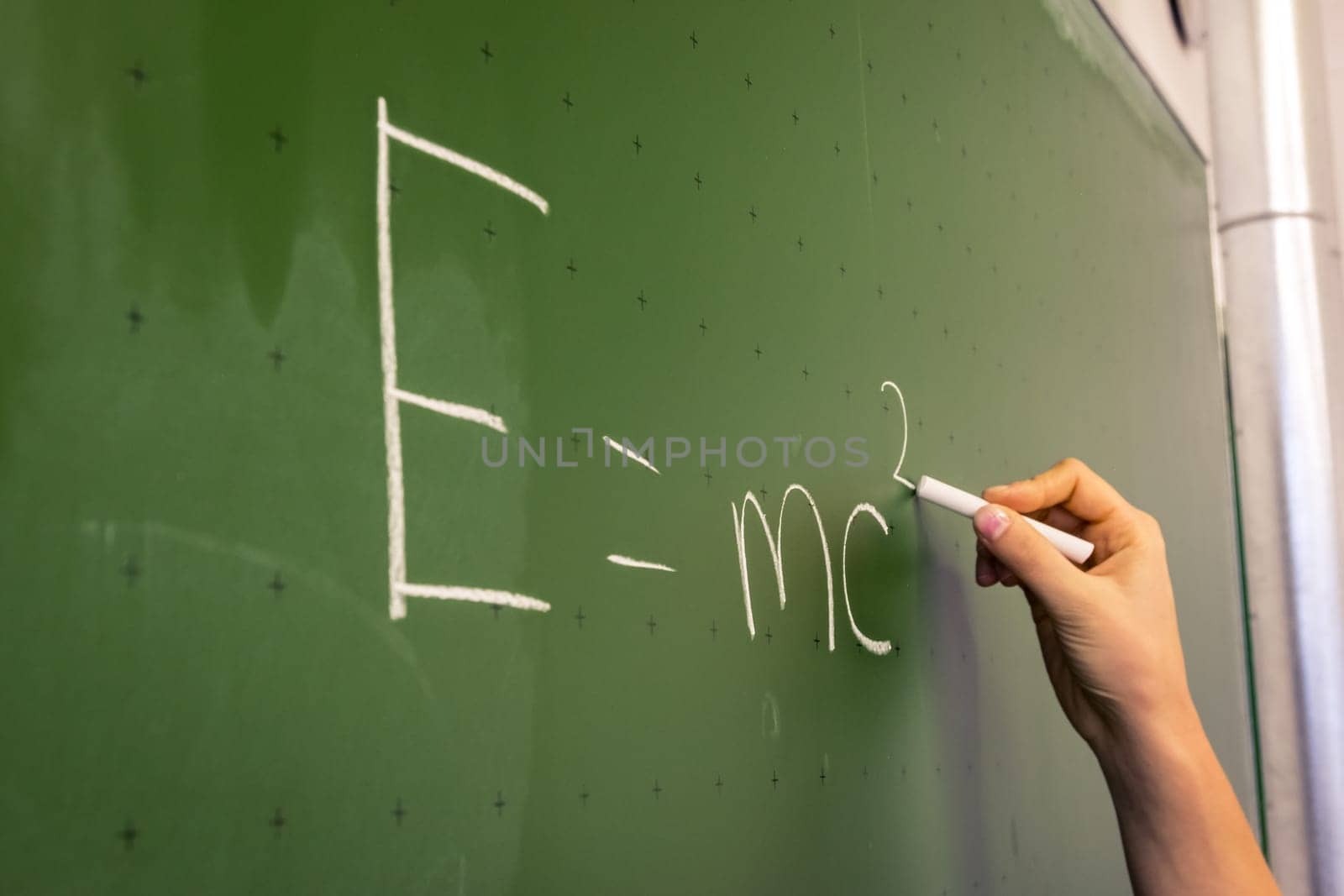Female Hand Teacher Writing on Green Chalkboard Professor University White Chalk College Education Lesson E = mc2