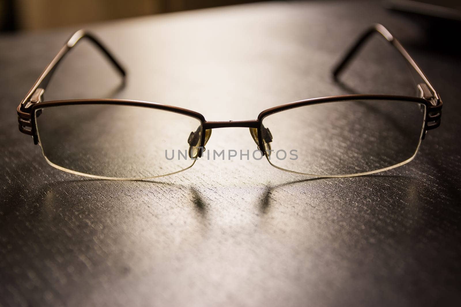 Brown Stylish Reading Glasses Setting on Black Desktop Workspace Empty Quiet