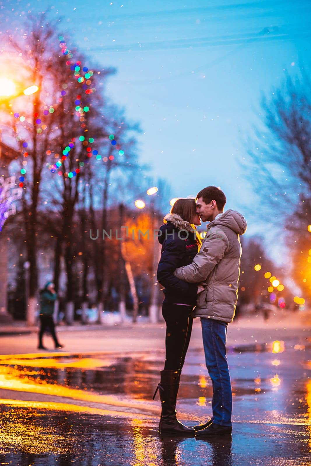 In love couple kissing in the snow at night city street. Filtered with grain and light flashing