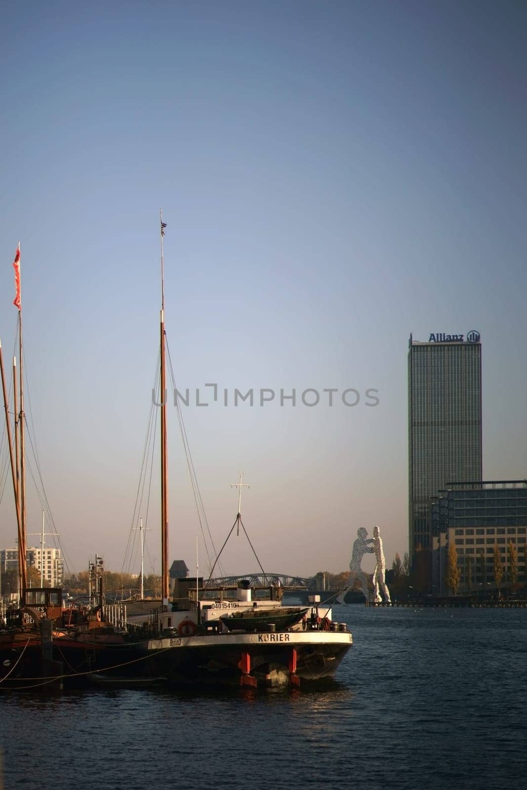 Berlin, Germany - November 06, 2018: Sailing ships on the banks of the Spree in front of the artwork "Molecule Man"" and the Allianz Hochhaus on November 06, 2018 in Berlin...."