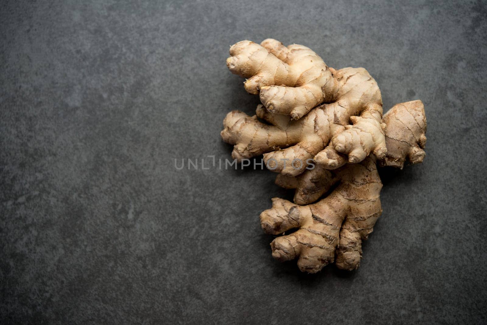 Top view fresh raw ginger root with copy space on dark background.