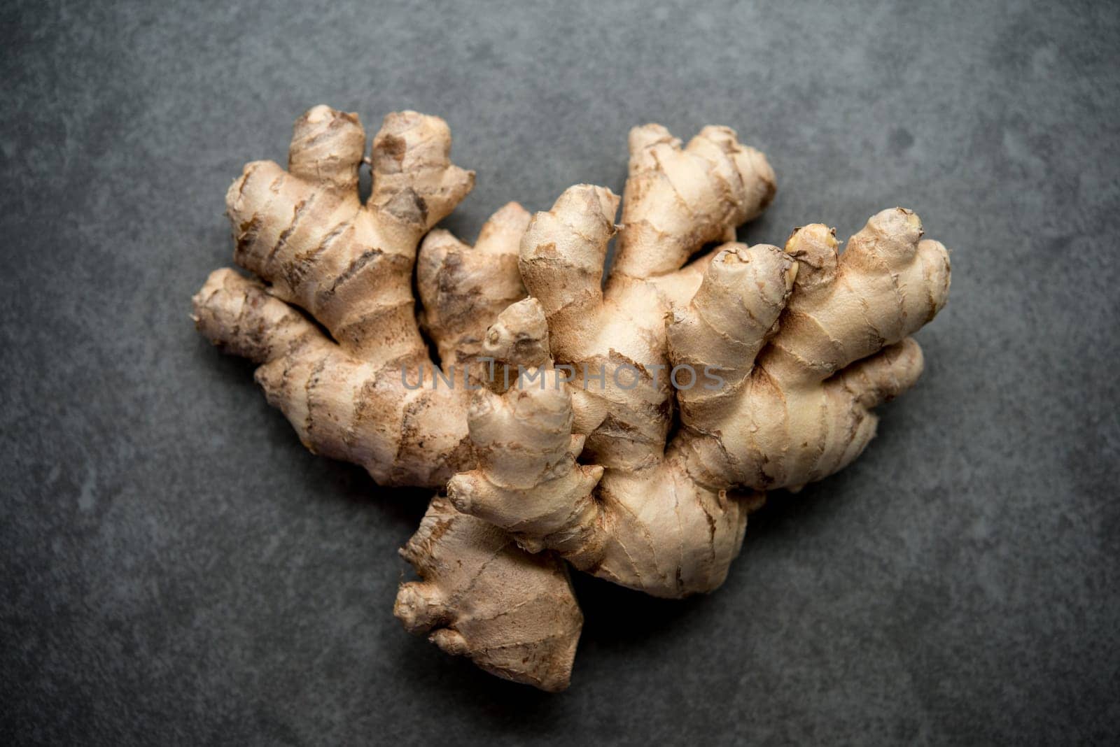 Flat lay fresh raw ginger root on dark background.