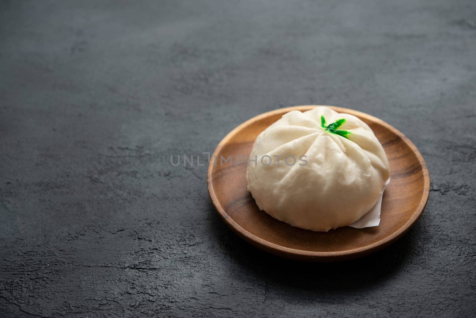 Baozi or bao dim sum on plate with copy space on dark background.