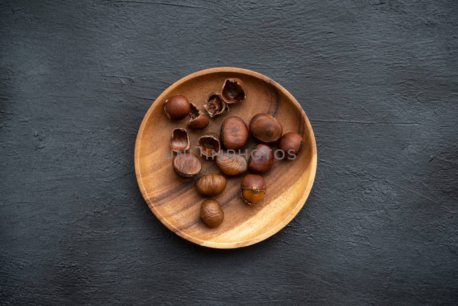 Top view chestnuts on plate with copy space on dark background.
