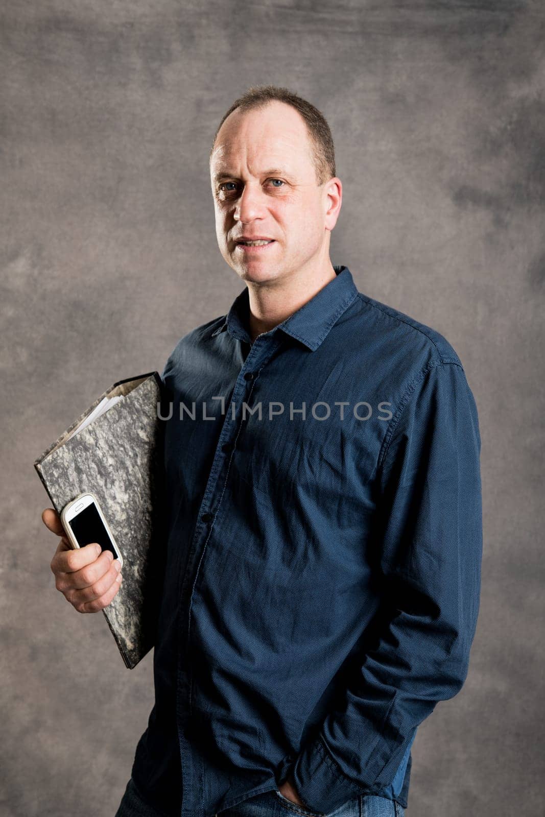 young businessman with folder,  phone in front of gray background