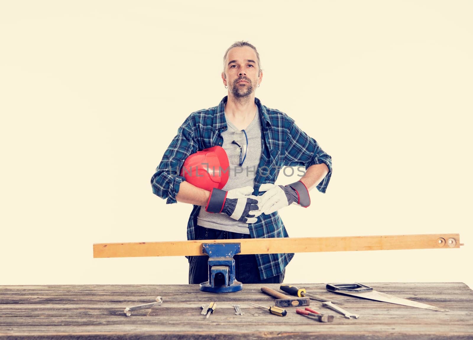 worker in blue plaid  shirt with red helmet on workbench