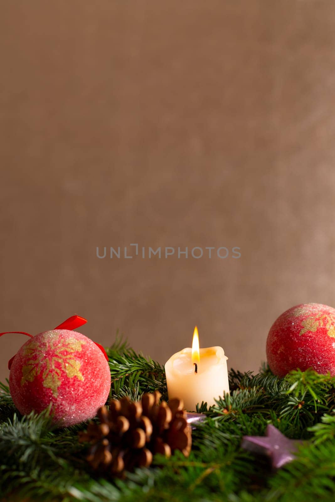 christmas decor with tree-balls, candle, branch and cone in front of golden background