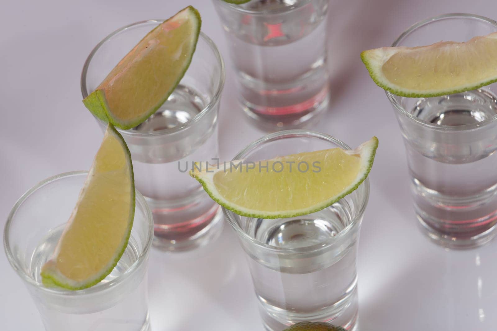 Tequila in glass with lime on white background
