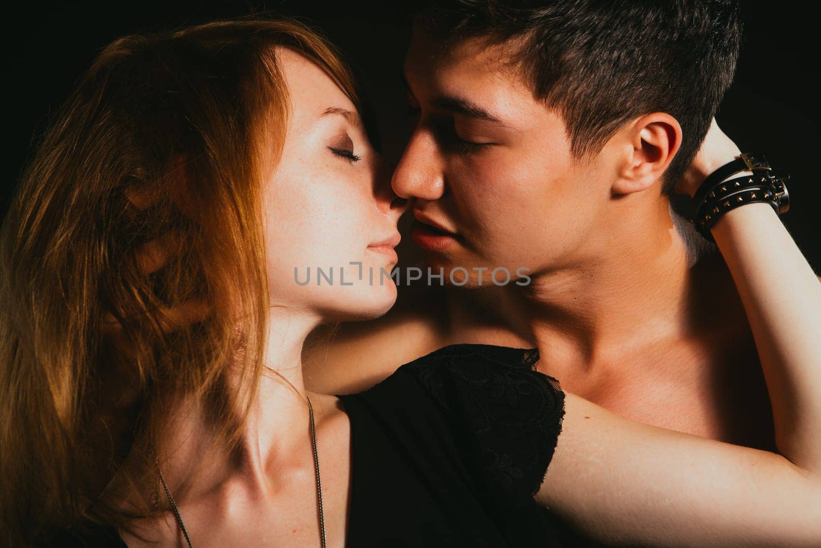 Young beautiful couple in each other's arms on a dark background