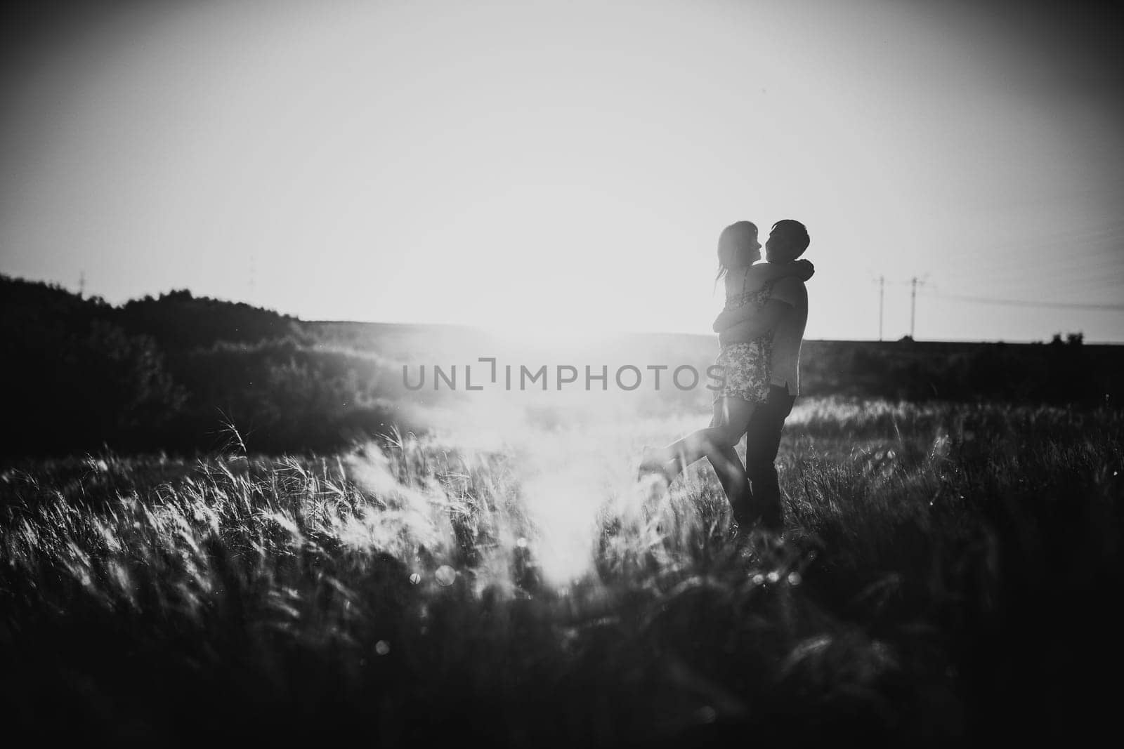 Black white photography romantic couple standing and kissing on background summer meadow sunset