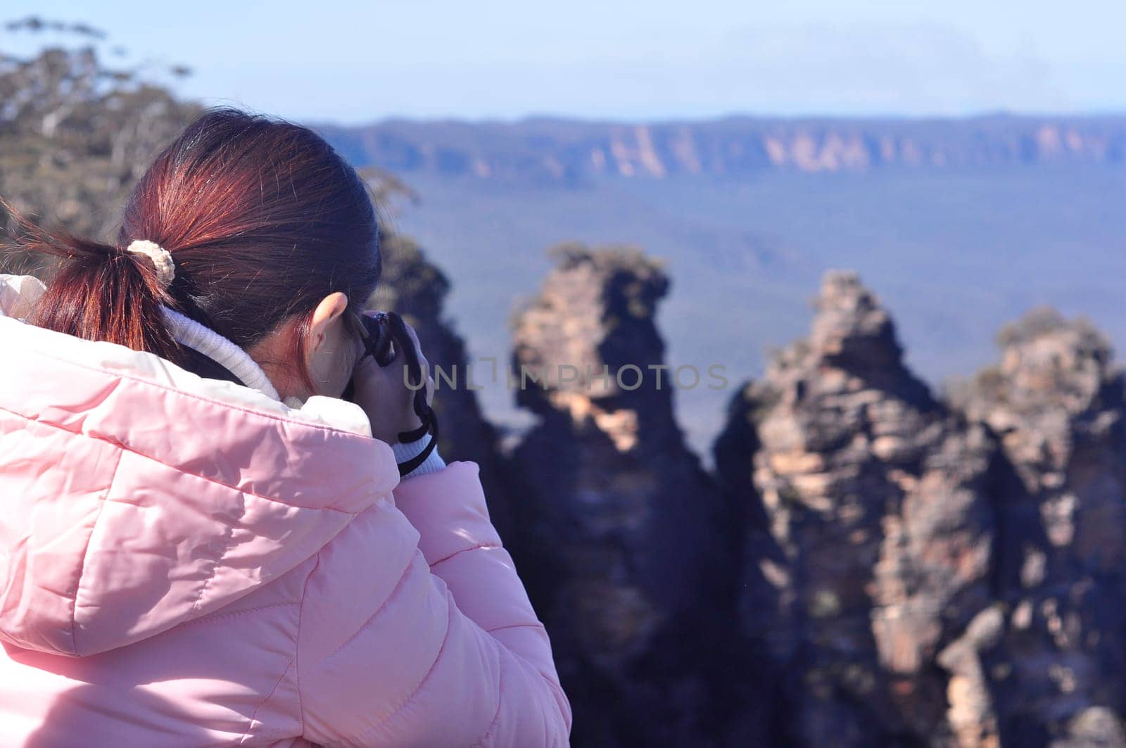 Young girl taking photo and enjoying scenic view of Three Sisters rock formation in the Blue Mountains National Parks near Sydney, New South Wales, Australia
