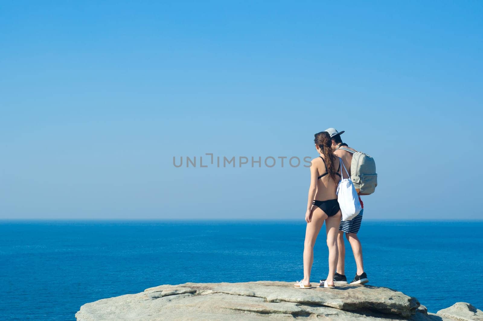 Hikers with backpacks enjoying the view of ocean. Traveling along mountains and coast, freedom and active lifestyle concept