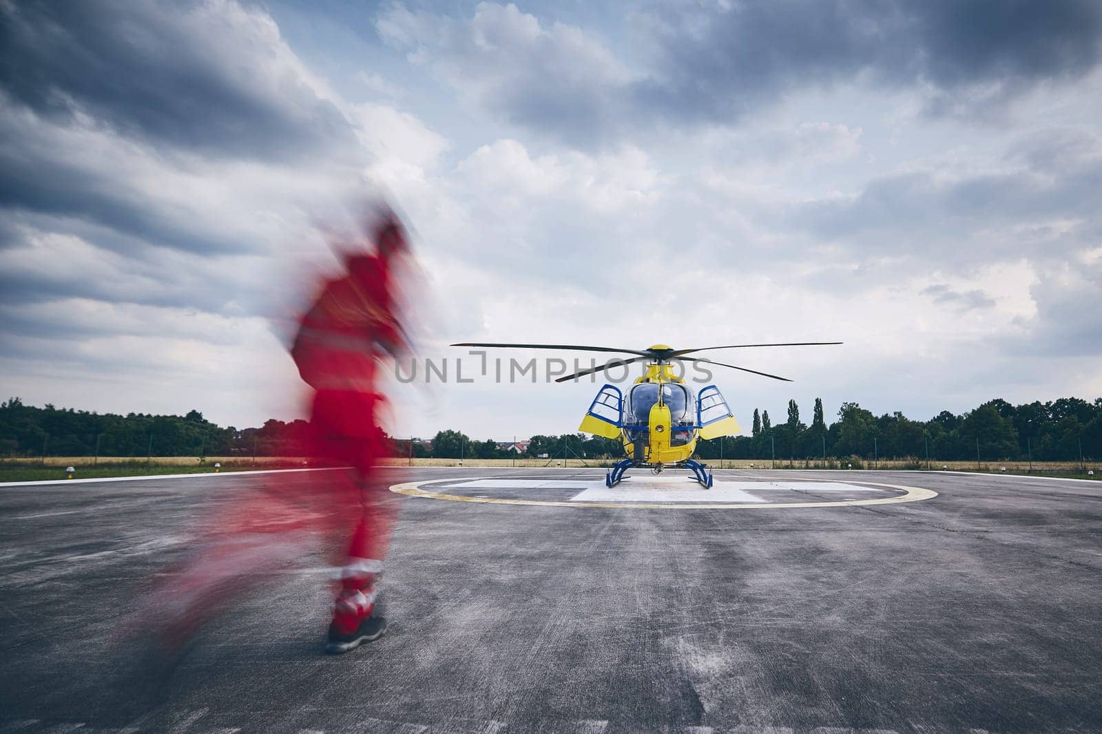 Alarm for helicopter emergency medical service. Paramedic running to helicopter on heliport.