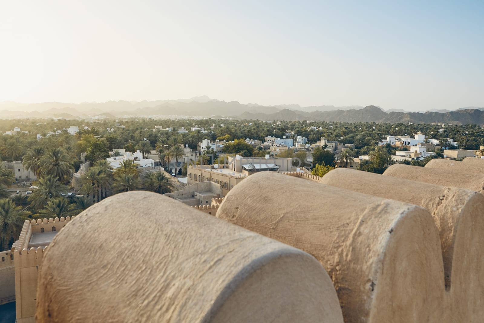 City against mountain range at idyllic sunset. Nizwa in Sultanate of Oman.