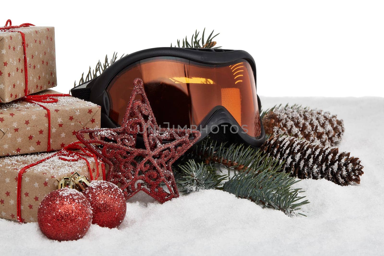 Winter holidays still life with gift boxes, fir tree branch, ski glasses and Christmas decorations lying on snow on a white background. New Year and Christmas. Winter vacation.