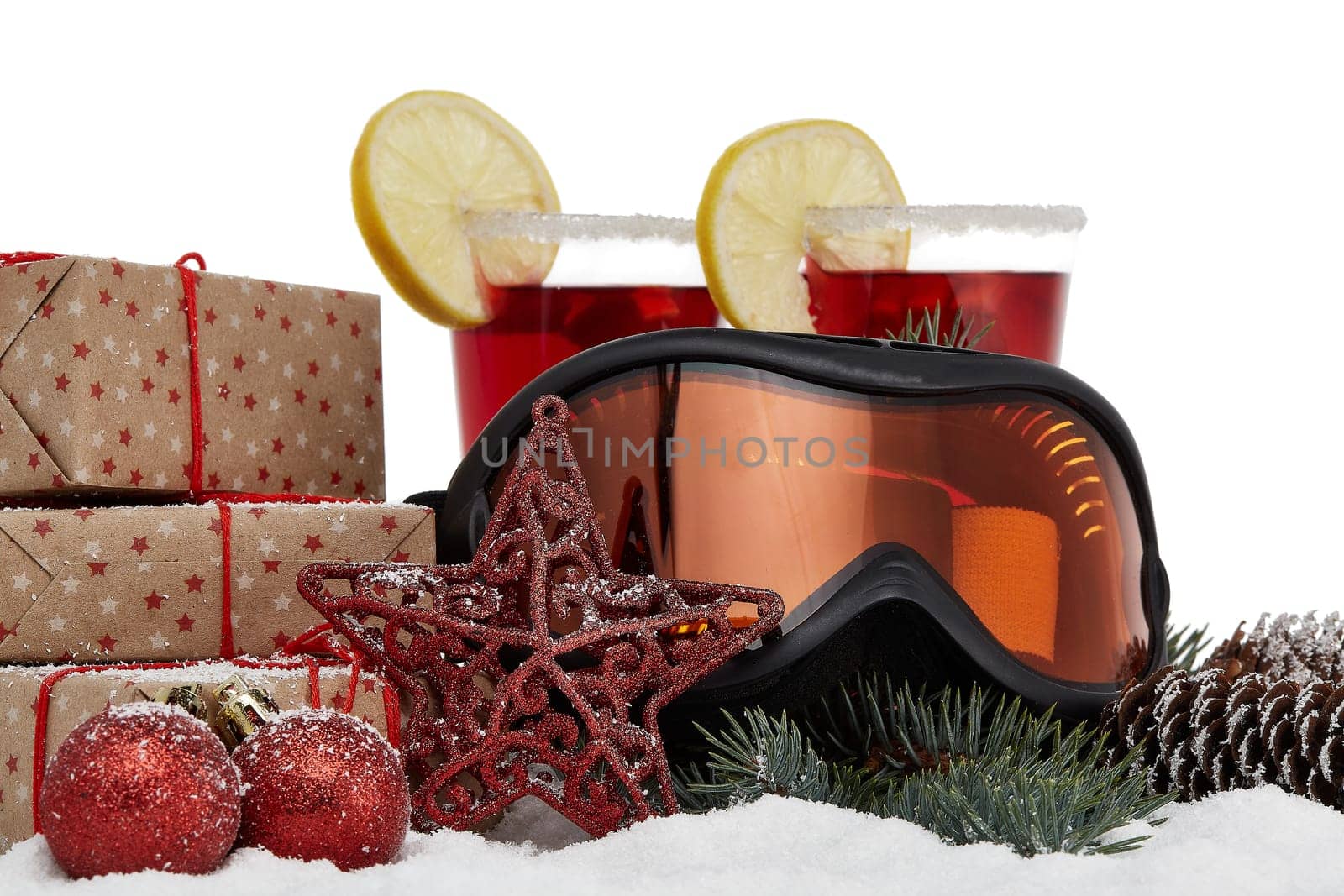 Winter holidays still life with gift boxes, fir tree branch, ski glasses, mulled wine and Christmas decorations lying on snow on a white background. New Year and Christmas. Winter vacation.