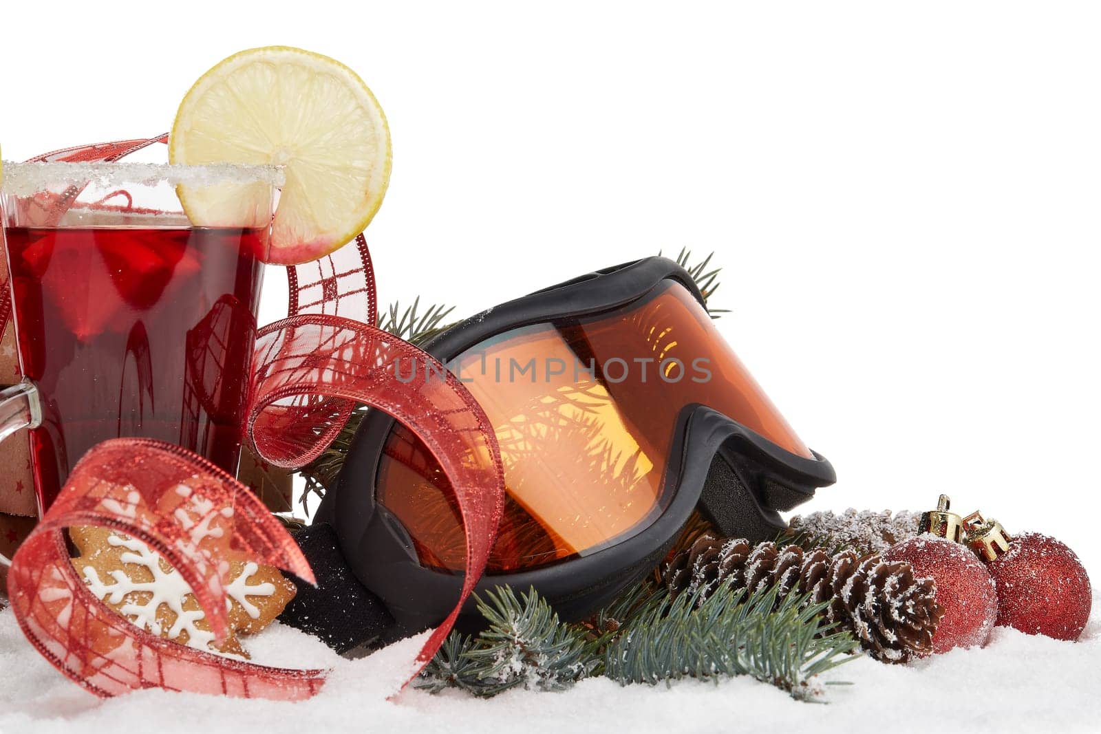 Winter holidays still life with fir tree branch, ski glasses, fruit tea, gingerbread cookies and Christmas decorations lying on snow with copy space. New Year and Christmas. Winter vacation.