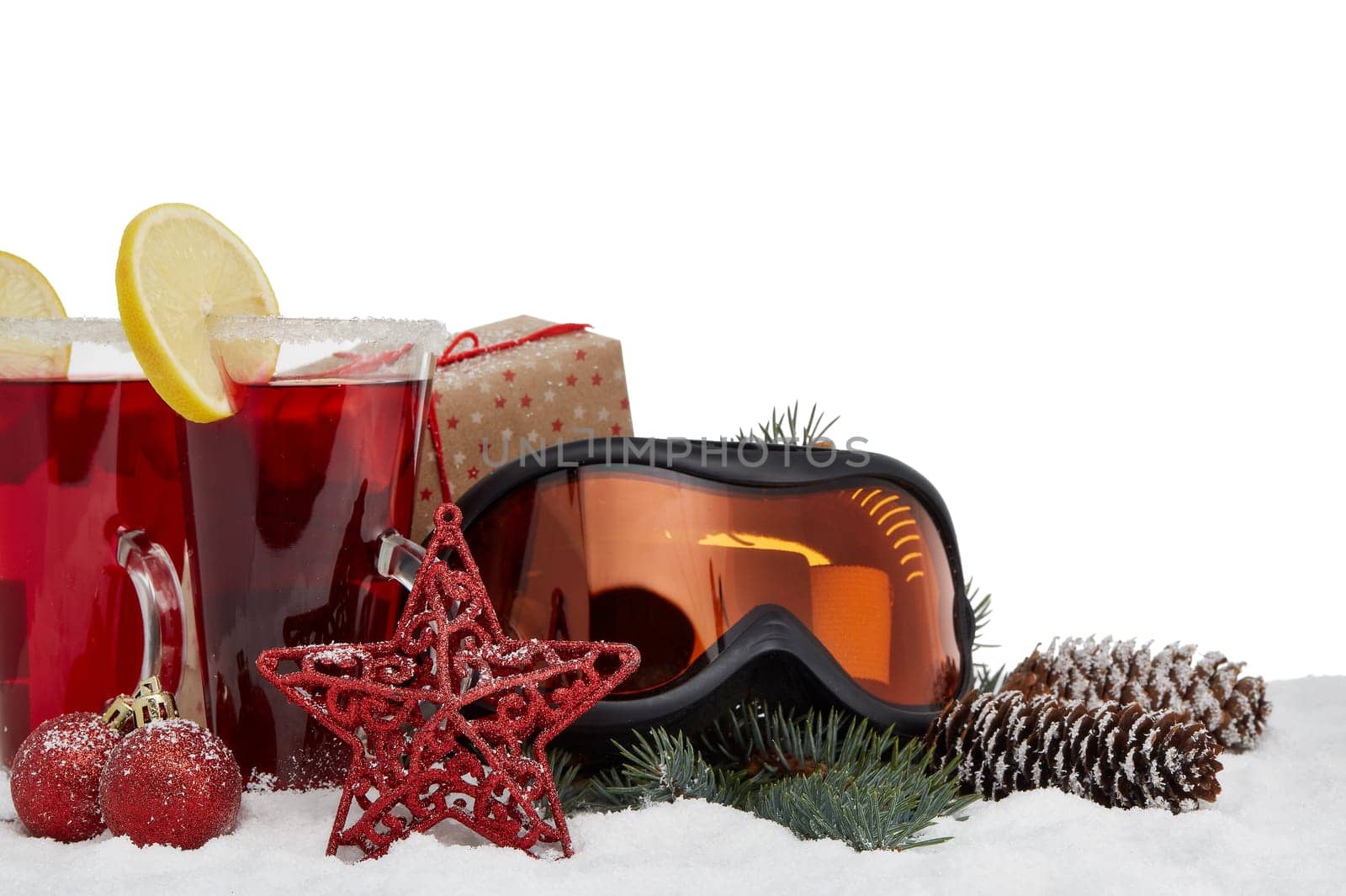 Winter holidays still life with gift boxes, fir tree branch, ski glasses, mulled wine and Christmas decorations on snow on a white background with copy space. New Year and Christmas. Winter vacation.