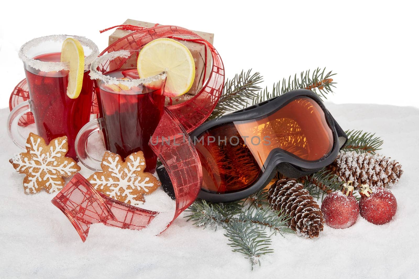 Winter holidays still life with fir tree branch, ski glasses, fruit tea, gingerbread cookies and Christmas decorations lying on snow with copy space. New Year and Christmas. Winter vacation.