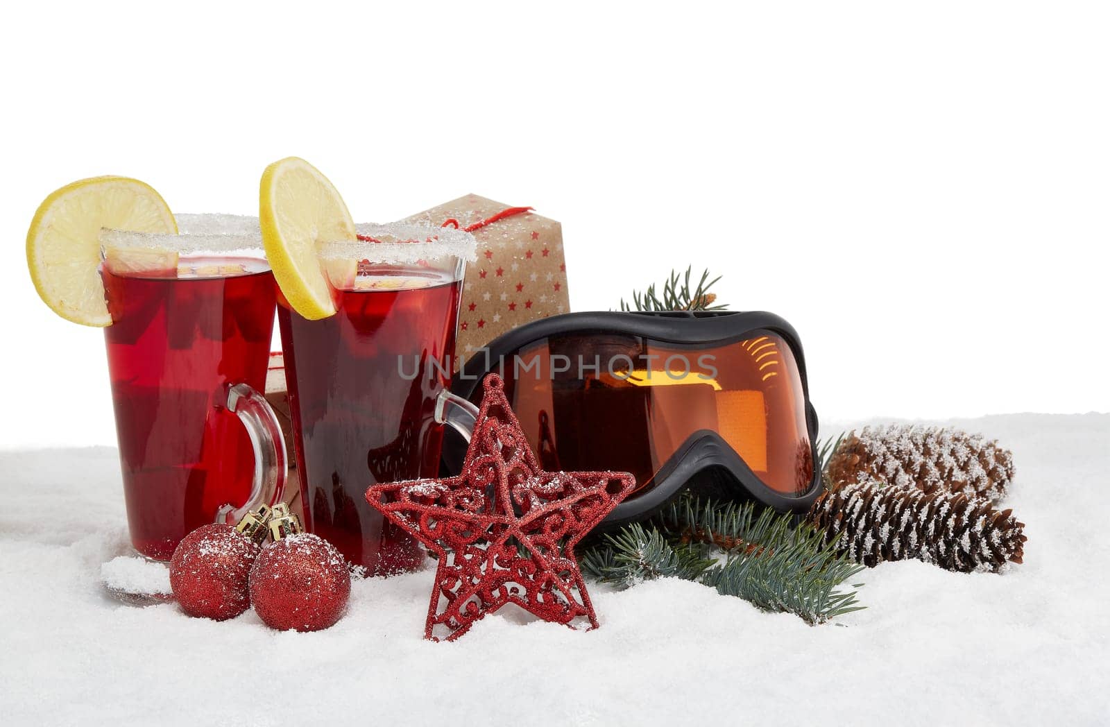 Winter holidays still life with gift boxes, fir tree branch, ski glasses, mulled wine and Christmas decorations on snow on a white background with copy space. New Year and Christmas. Winter vacation.