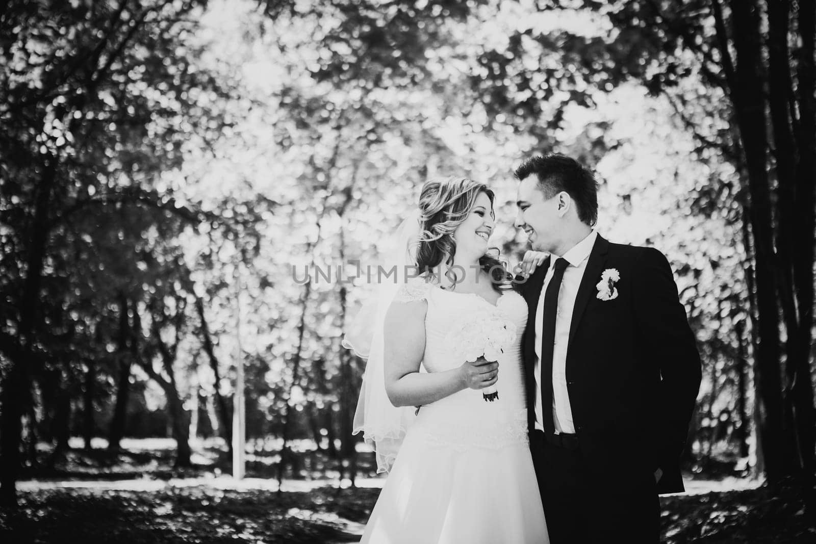 Black white photography happy couple bride and groom embracing they stand in a forest