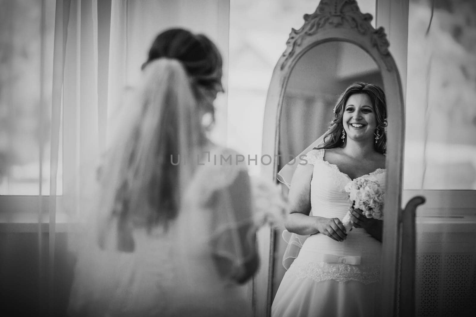 Black white photography elegance cute bride holding a bouquet looks in the mirror