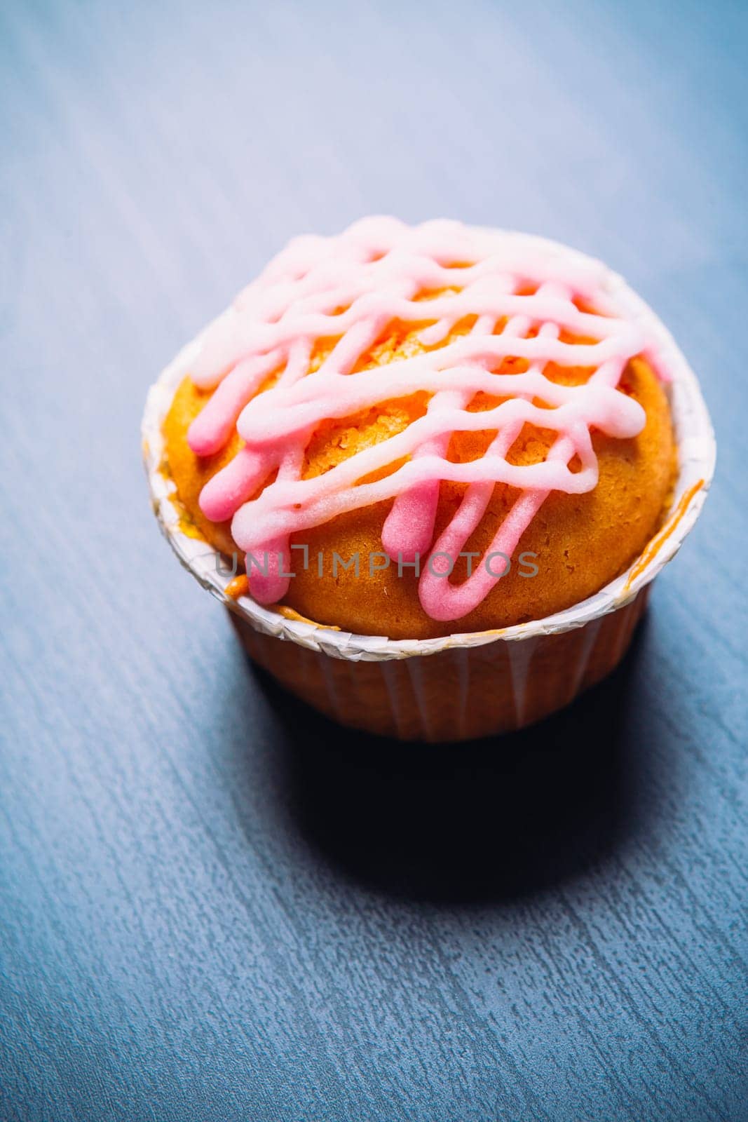 cupcake with pink frosting on a wooden background