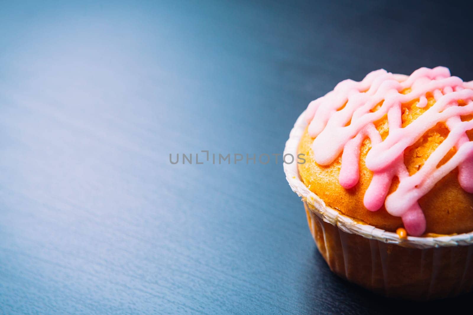 cupcake with pink frosting on a wooden background