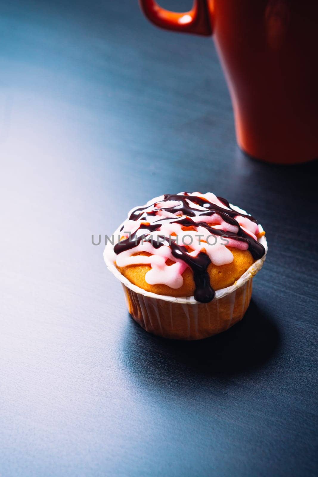 cupcake with pink frosting and red cup on a wooden background